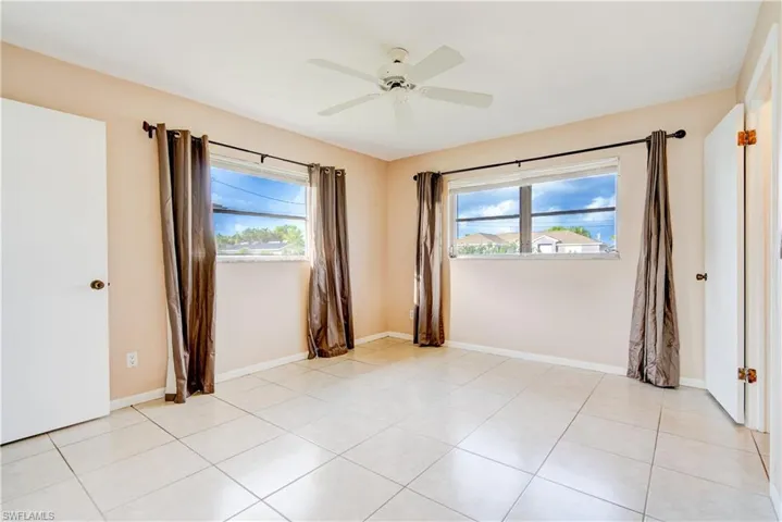Unfurnished room featuring healthy amount of natural light, light tile patterned flooring, and ceiling fan