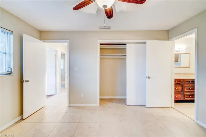 Unfurnished bedroom with ceiling fan, light tile patterned floors, and a closet