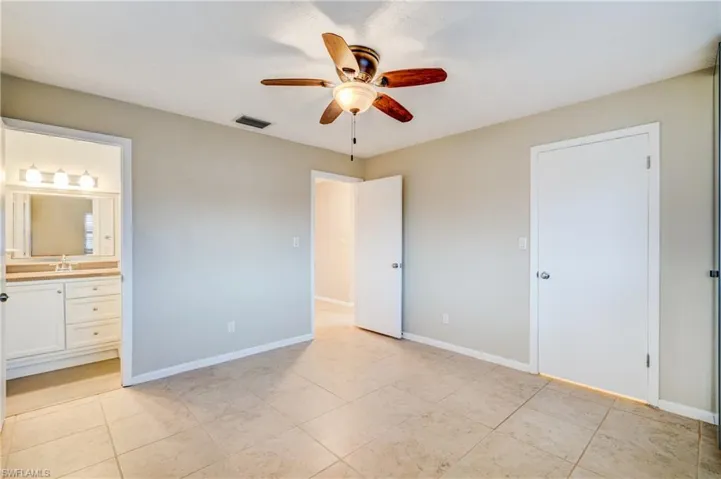 Unfurnished bedroom featuring ceiling fan, sink, light tile patterned floors, and ensuite bathroom