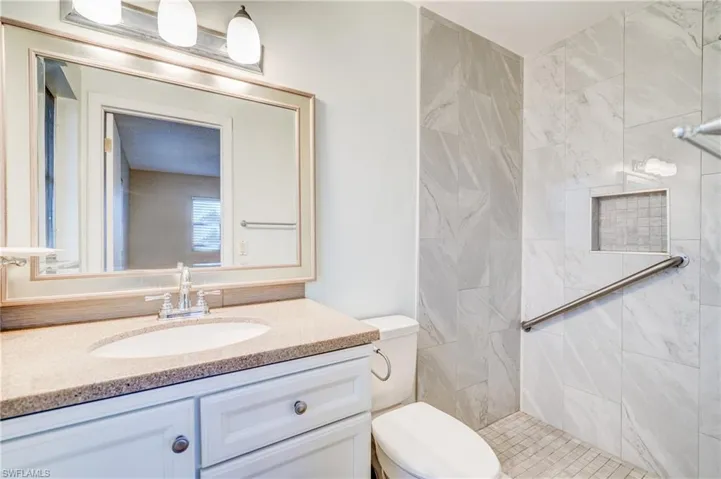 Bathroom featuring a tile shower, toilet, and vanity