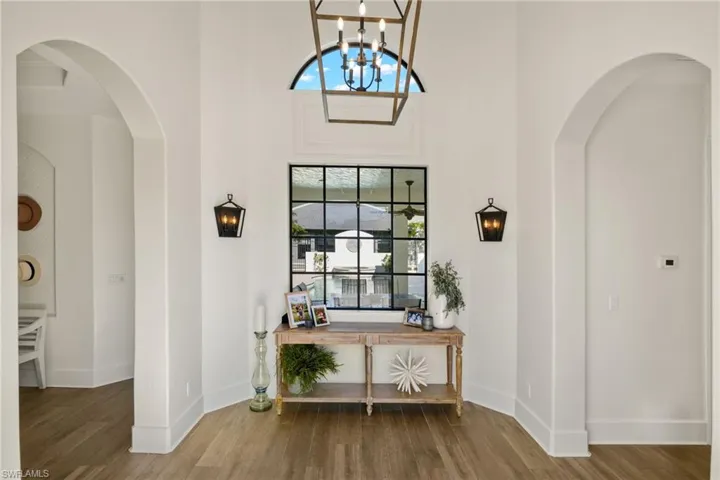 Foyer entrance with hardwood / wood-style flooring, a high ceiling, and an inviting chandelier