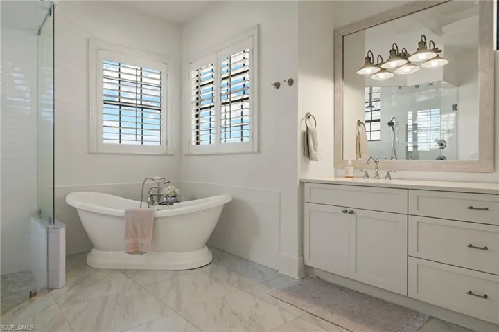 Bathroom featuring shower with separate bathtub, vanity, and tile walls