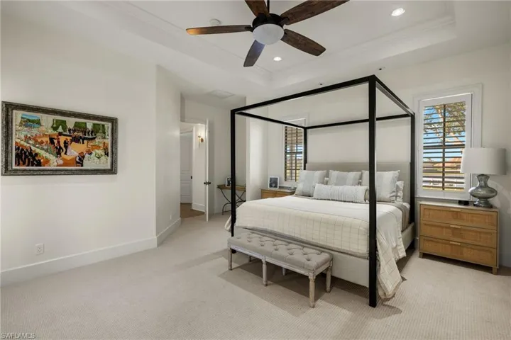 Bedroom with a raised ceiling, ceiling fan, crown molding, and light carpet