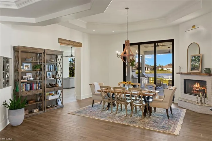 Dining space with a raised ceiling, a chandelier, dark wood-type flooring, and ornamental molding