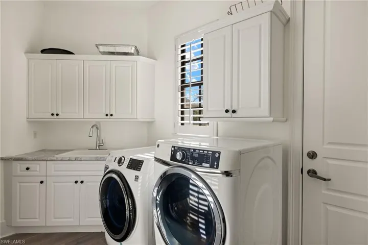 Downstairs Laundry room with washer and dryer, sink, cabinets, and dark hardwood / wood-style floors