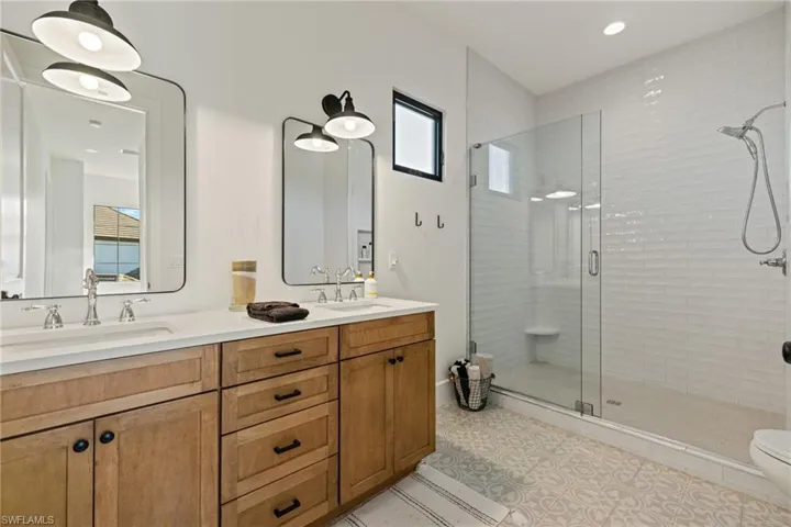 Bathroom with vanity, toilet, plenty of natural light, and a shower with shower door