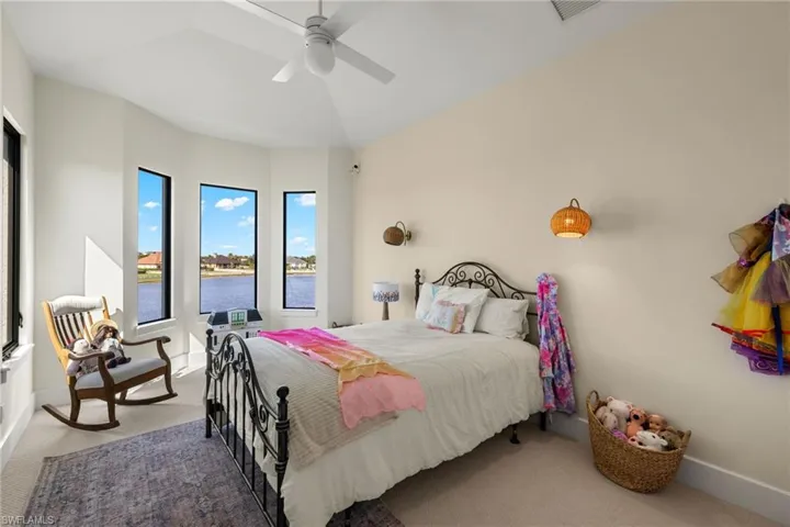 Carpeted bedroom with a water view and ceiling fan