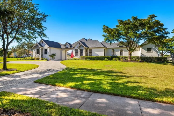 Large two story home featuring a front yard, garage, and courtyard pool.