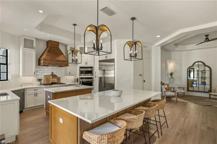 Kitchen with premium range hood, stainless steel appliances, a raised ceiling, white cabinets, and a kitchen island