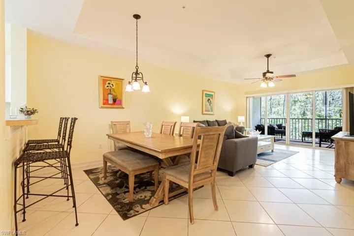 Dining area featuring a raised ceiling, light tile patterned flooring, and ceiling fan