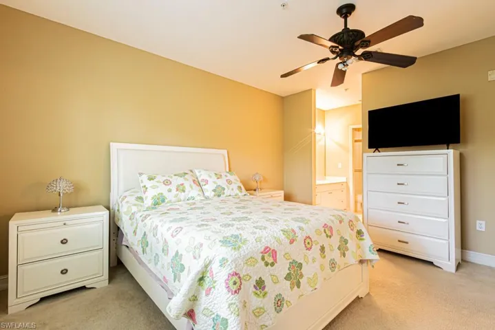 Bedroom featuring light colored carpet, ensuite bathroom, and a ceiling fan