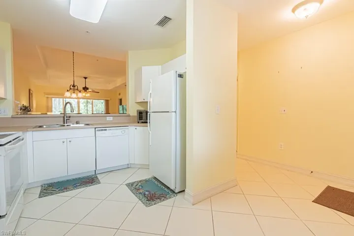 Kitchen featuring white appliances, light tile patterned floors, white cabinets, and light countertops