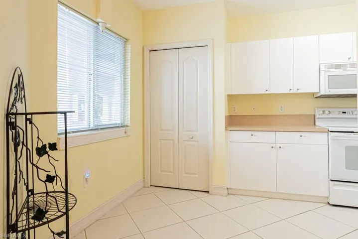 Kitchen with white appliances, light countertops, white cabinetry, and light tile patterned flooring