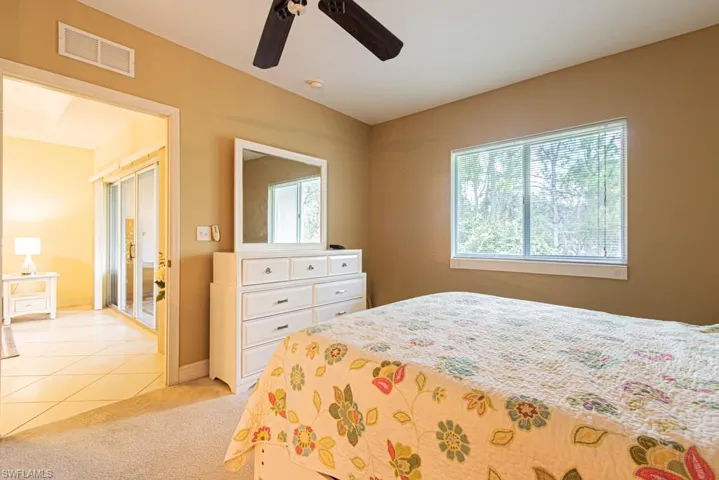Bedroom with light tile patterned floors, light carpet, and a ceiling fan