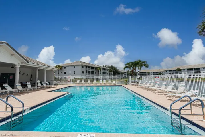 Community pool with a patio area, a ceiling fan, and a residential view