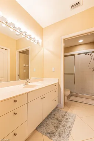 Bathroom featuring light tile patterned flooring, vanity, and a stall shower