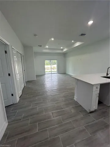 Spare room with a tray ceiling, recessed lighting, and wood finish floors