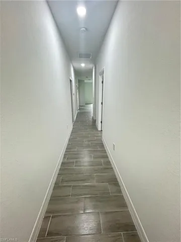 Hallway featuring wood finish floors and baseboards