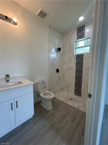 Bathroom featuring a tile shower, vanity, and recessed lighting