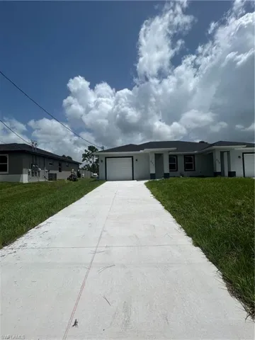 Ranch-style house featuring an attached garage, concrete driveway, stucco siding, and a front yard