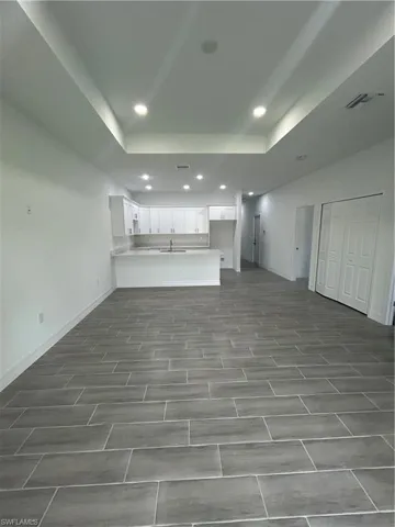 Unfurnished living room featuring recessed lighting and a raised ceiling