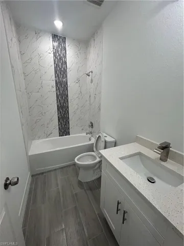 Full bath with vanity, shower / bathtub combination, and wood tiled floors