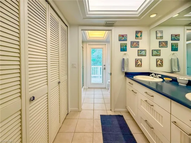 Half bathroom with vanity, tile patterned flooring, and a tray ceiling