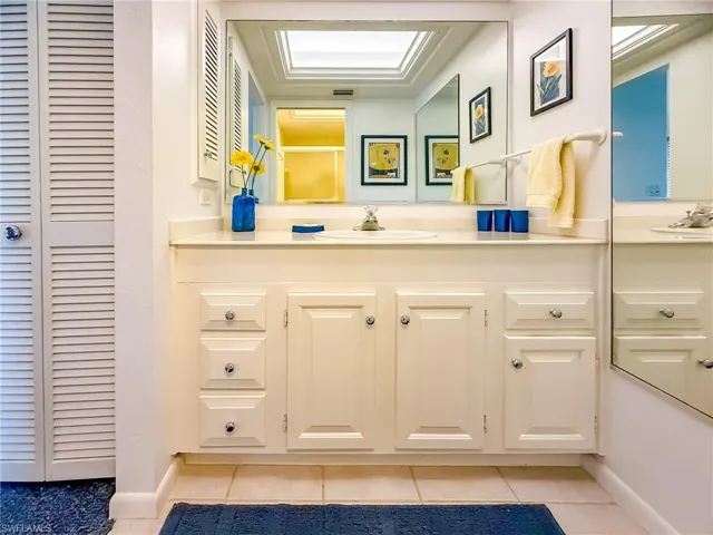 Kitchen featuring white appliances, washer and clothes dryer, dark countertops, light tile patterned floors, and white cabinets