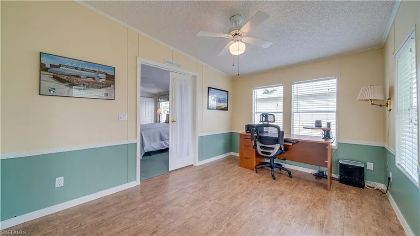 Steps away from the primary bedroom, through the French doors, a large bonus space. Notice the chair railing, the flooring, and the neutral paint tones?