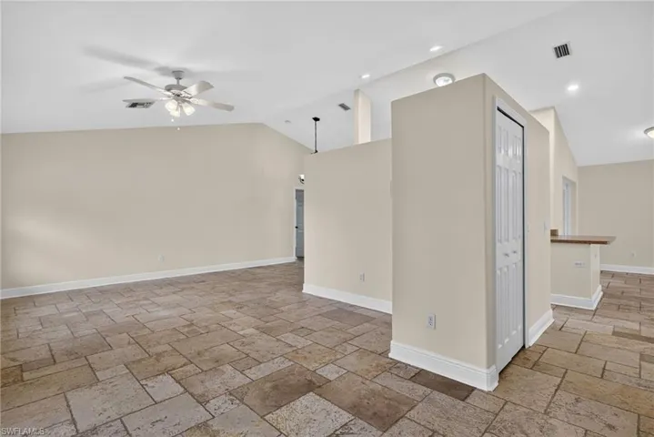 Entryway with front living room to left, coat closet center, and passage to kitchen and rear living room on right