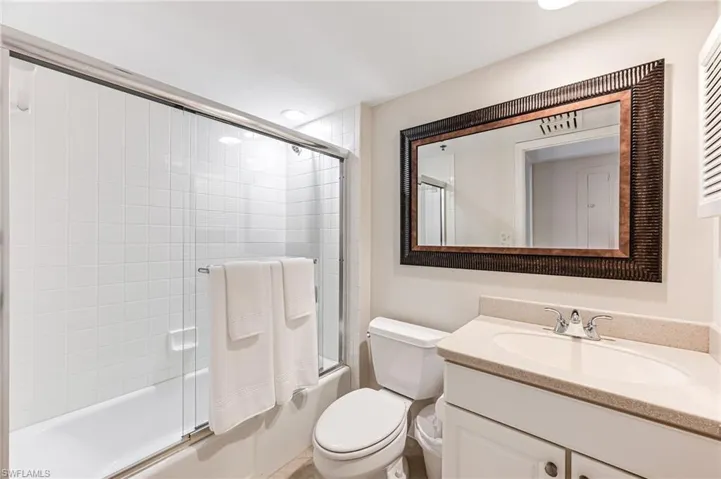 Full bathroom with vanity, toilet, and bath / shower combo with glass door