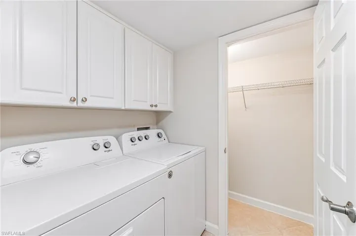 Laundry room featuring independent washer and dryer, light tile patterned flooring, and cabinets