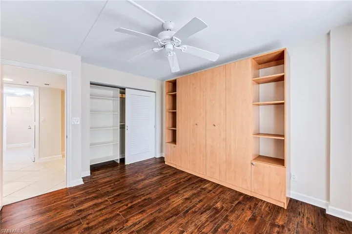 Unfurnished bedroom with a closet, ceiling fan, and dark hardwood / wood-style flooring
