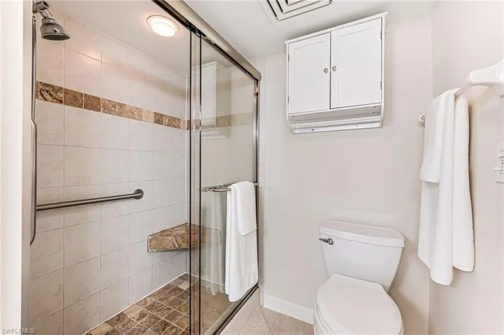 Bathroom featuring a shower with door and toilet