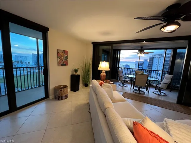 Tiled living room with ceiling fan and floor to ceiling windows