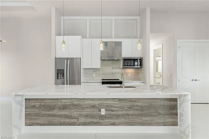 Stainless steel appliances, quartz countertops, waterfall island.