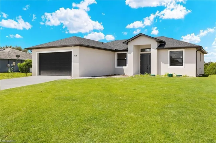 View of front of home featuring a front lawn, an attached garage, stucco siding, concrete driveway, and roof with shingles