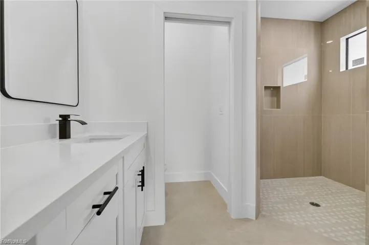 Bathroom with a walk in shower, vanity, and light tile patterned flooring