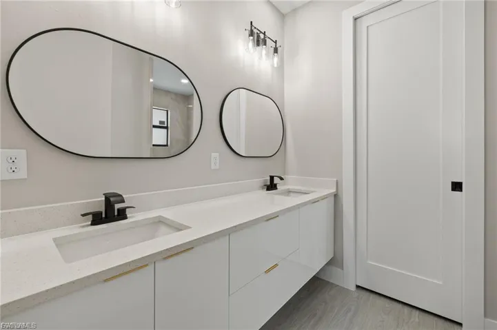 Full bath featuring double vanity and light wood finished floors