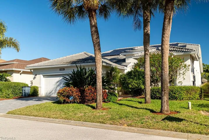 View of front of house with stucco siding, a tile roof, a front lawn, driveway, and a garage