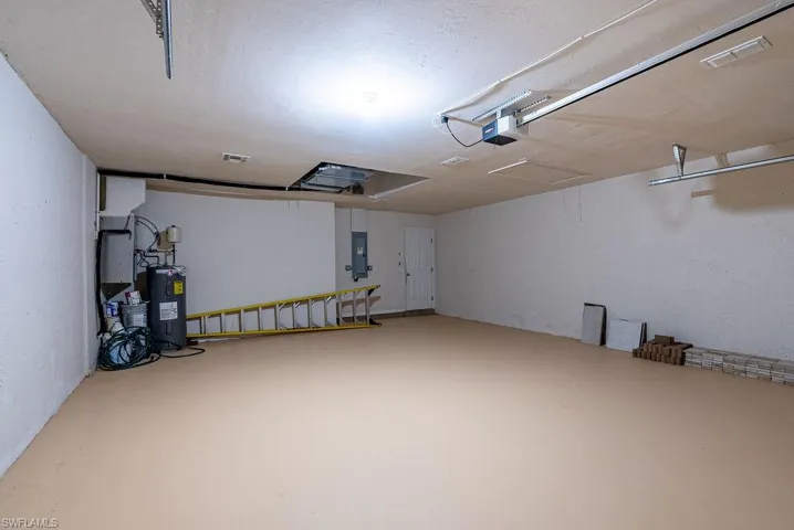 Garage featuring water heater, electric panel, and a garage door opener