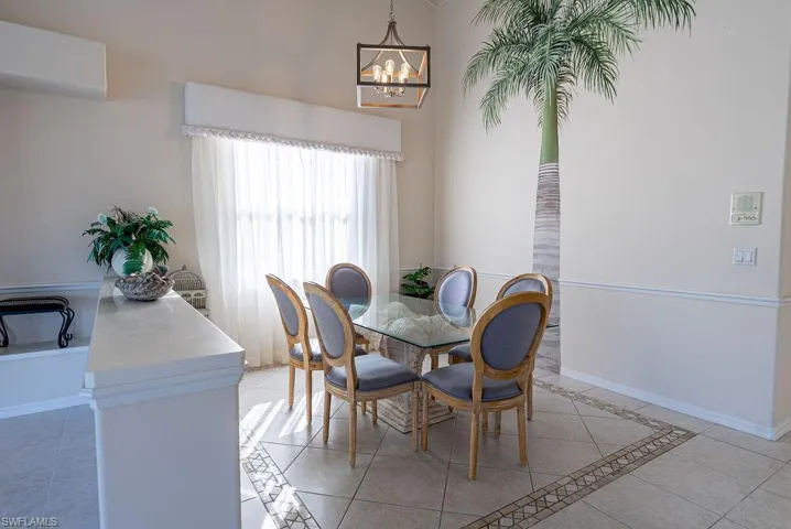 Dining space with inlaid floor details, light tile patterned flooring, an AC wall unit, and a chandelier