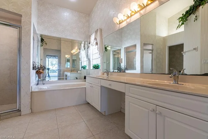 Full bathroom with a garden tub, wallpapered walls, a stall shower, light tile patterned flooring, and double vanity
