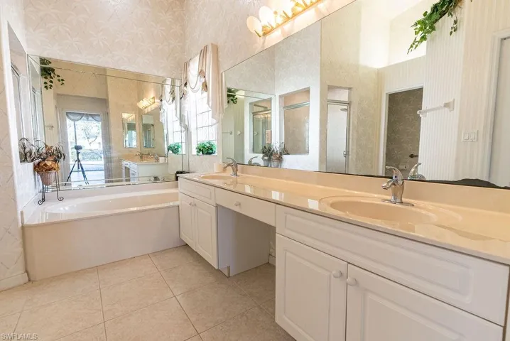 Bathroom with wallpapered walls, a garden tub, double vanity, a shower stall, and light tile patterned floors