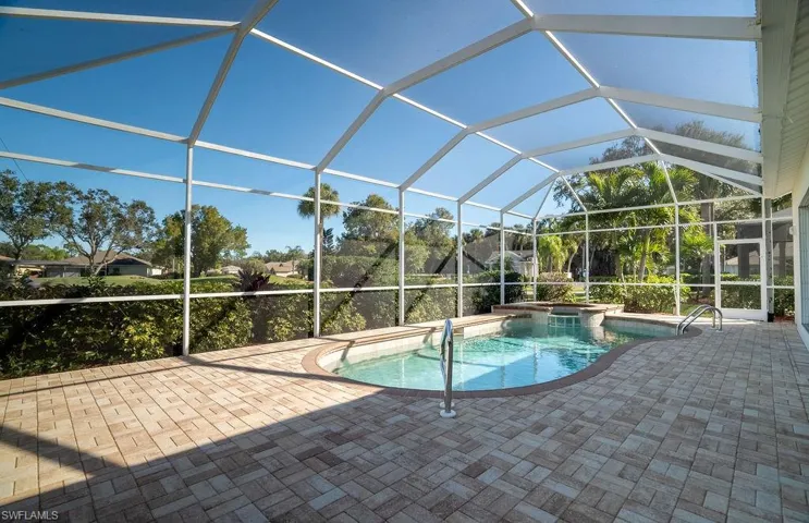 View of pool featuring a sunroom, glass enclosure, a pool with connected hot tub, and a patio