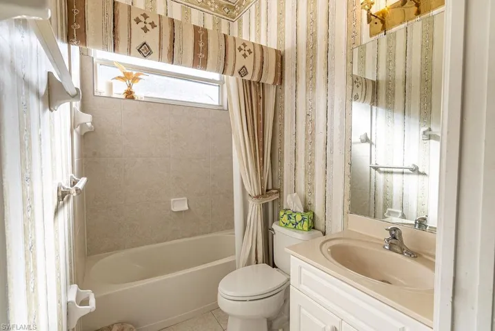 Full bath with vanity, shower / bath combination with curtain, and wallpapered walls