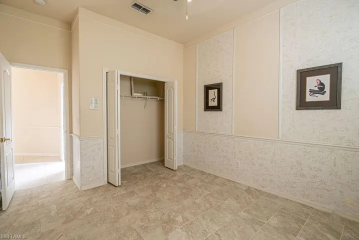 Unfurnished bedroom with wallpapered walls and a closet