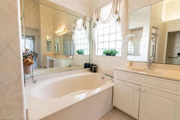 Full bath featuring wallpapered walls, a bath, vanity, and a stall shower