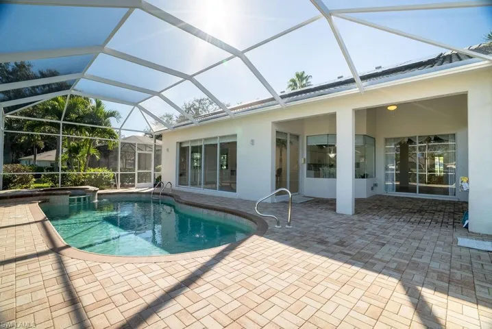 View of swimming pool with glass enclosure, a sunroom, a patio area, and a pool with connected hot tub