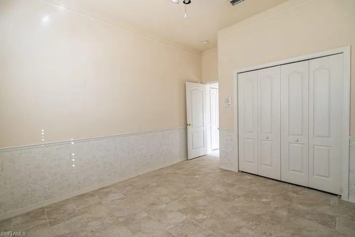 Unfurnished bedroom with a wainscoted wall and a closet